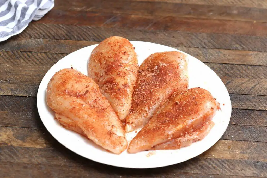 Condire i petti di pollo crudo con paprika, aglio in polvere, sale e pepe.